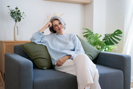 Elegant woman relaxing on sofa in calm living room with gentle light