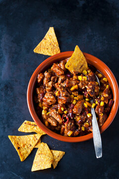 Vegetarian Chili with soy meat cut into strips and tortilla chips in earthenware dish