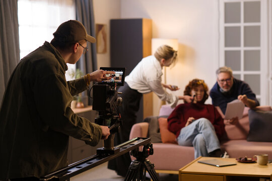 Cameraman films an interview with an actress on a living room set