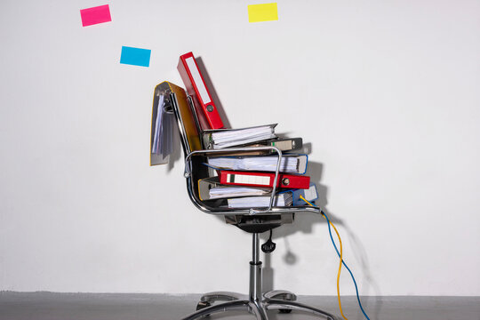 Office chair stacked with files and cables showing digitalization