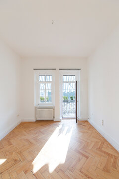 Empty room with herringbone parquet and opened balcony door