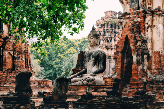 Thailand, Ayutthaya, Buddha statue surrounded by brick pagodes at Wat Mahathat