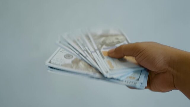 Male hands waving a stack of dollar bills against a white background. Cash payments, savings, financial planning, investing and money management concept. 4K video slow motion.