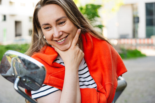 Smiling woman looking in a mirror outdoors with self confidence