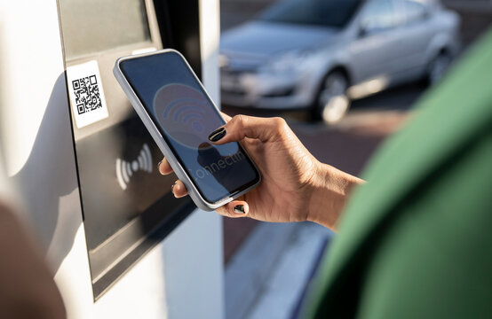 Commuter scanning QR code on smart phone at gas station