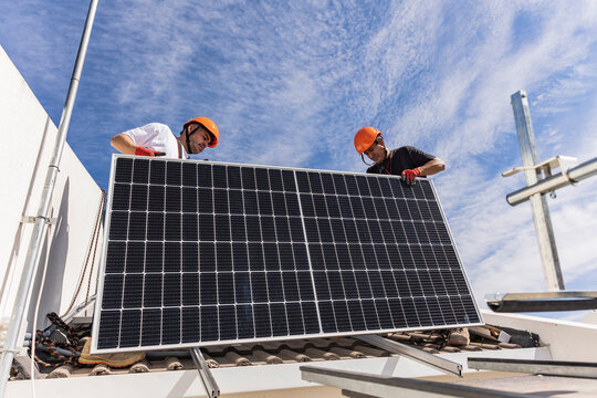Engineer with colleague holding solar panel on roof
