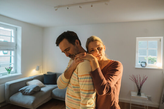 Sad mature couple standing in living room at home