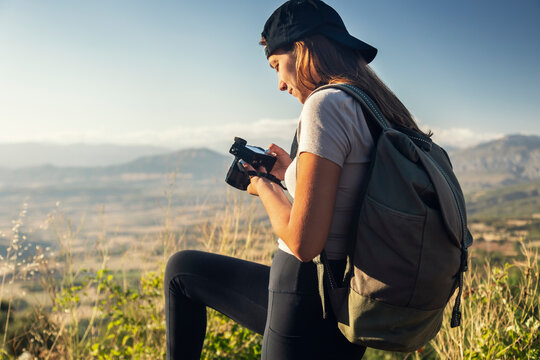 Young tourist with backpack and camera hiking on sunny day