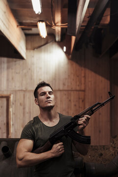 Portrait of man holding a rifle in an indoor shooting range