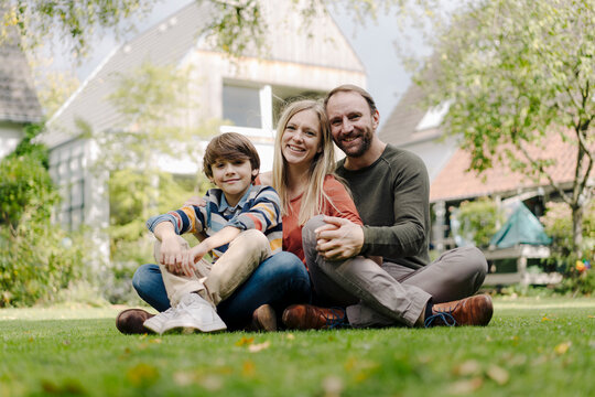 Happy family sitting on grass in their garden