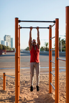 Fit man working out in climbing parcour, doing pull ups