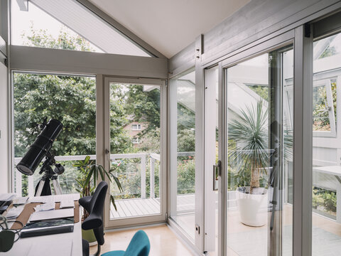 Modern home office with telescope and large windows