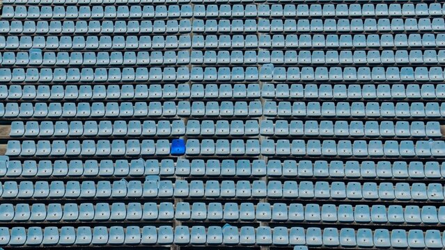 One dark blue seat stands out in an empty stadium grandstand