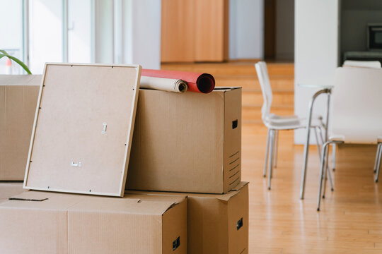 Packed moving boxes sit on a wooden floor in a new apartment
