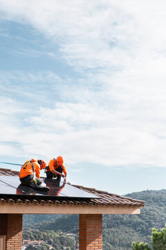 Workers installing solar panels on roof in Barcelona with teamwork