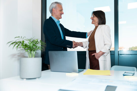 Senior businessman and businesswoman shake hands in the office