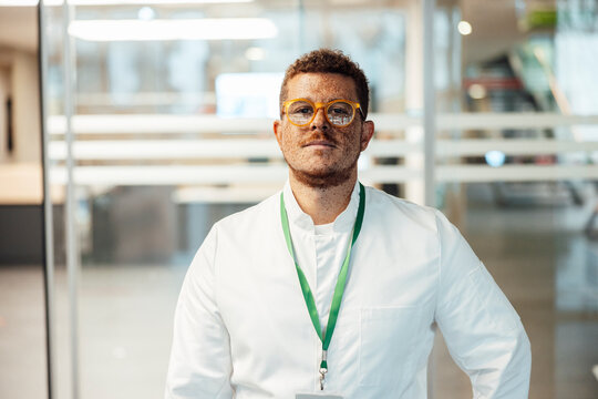Doctor with freckles in lab coat indoors at hospital looking at camera