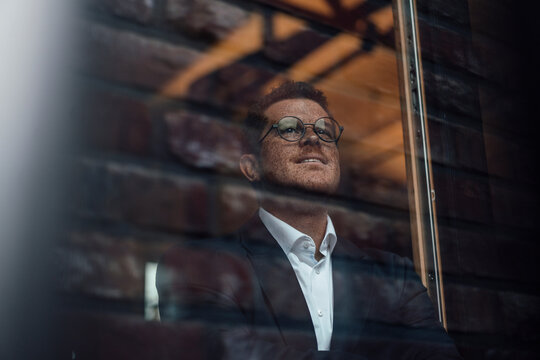 A businessman with freckles looks out the office window