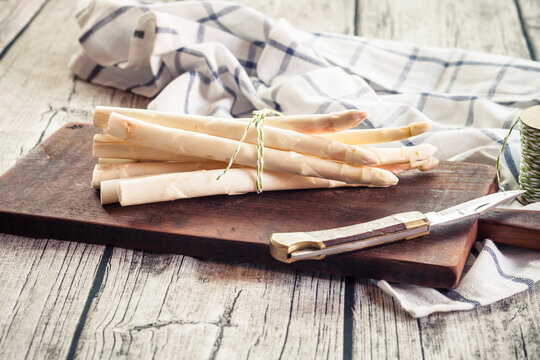 Bunch of white asparagus on wooden chopping board