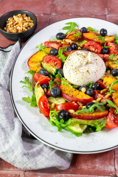A fresh summer salad features burrata cheese and nectarine on a plate
