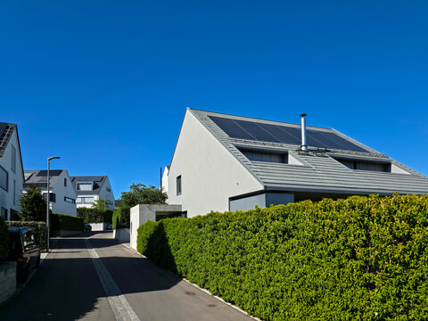 germany, contemporary residential homes with photovoltaic roofs in ostfildern kemnat surrounded by vibrant summer nature beneath cloudless blue sky