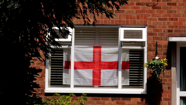 England flag, St George's Cross in house window, red brick facade, British residential building facade, football tournament support concept