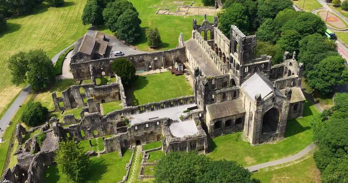 Aerial drone footage of Kirkstall Abbey in Leeds West Yorkshire England capturing the spectacular medieval Cistercian monastery ruins from above with surrounding parkland during the summer