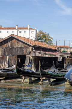 Gondolas in repair at a workshop in Venice during a sunny day by the water
