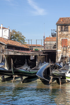 Gondolas in repair at a workshop in Venice during a sunny day by the water