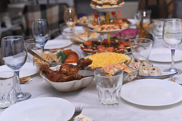 Fototapeta premium Assorted party food served on white tablecloth during holiday dinner. Many delicious dishes like meat snacks and fresh salads are ready for guests. Gourmet catering service for big banquet.