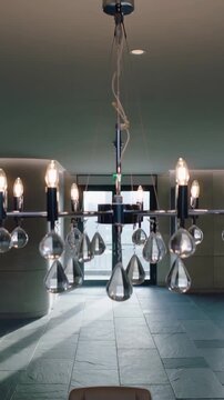 Vertical video: Tilting camera revealing crystal chandelier over table in hall, showing gold bowl
