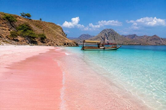 Traditional Wooden Boat Anchored at Pink Sand Beach with Turquoise Water, Komodo Island Indonesia