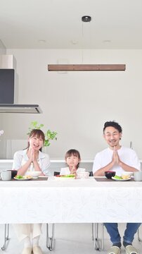 [音声付き いただきます]いただきますをしてダイニングで座る食事を始める親子3人の家族・食育や家族団らんのカメラ目線イメージクローズアップ縦動画
