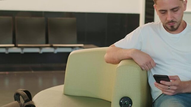 Man in airport lounge seated near charging station plugging in smartphone while waiting for flight modern travel technology convenient infrastructure and digital mobility for connected journeys