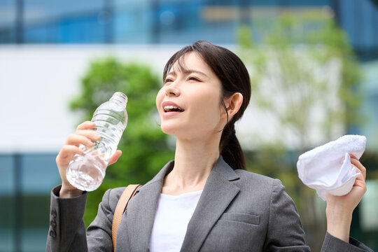 暑い屋外で水を飲むビジネスウーマン