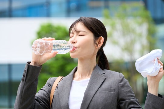暑い屋外で水を飲むビジネスウーマン
