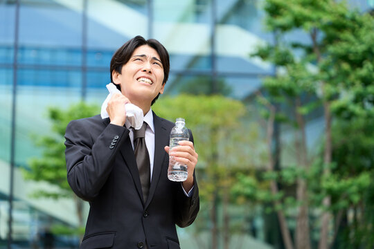 暑い屋外で汗を拭くビジネスマン