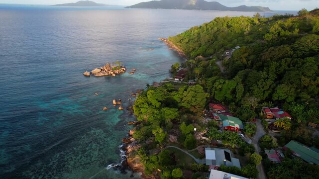 Houses in the coast of Praslin island at sunset, Seychelles. Aerial tilt up