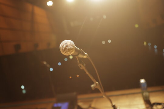 Microphone standing on stage, ready for a performance under warm lights