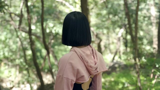 A lone backpacker treks does not know which way to go through shadowy green forest, woman looks around lost in the woods, puzzled hiker is worried about the coming twilight, fear feeling lost the path