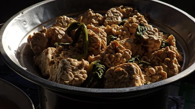 Still close up of raw fermented Glycine max tempeh inside a metal strainer with natural light highlighting texture