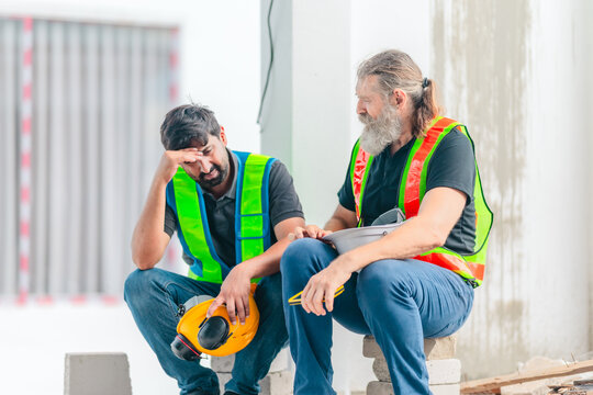 Exhausted construction workers with burnout resting tired and stressed at house building site