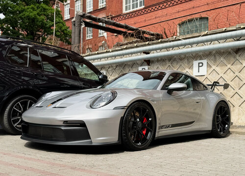 Porsche 911 RS GT3 silver sports car parked on parking lot. Silver sport coupe Porsche 991 GT3 RS on parking lot. Luxury German sport coupe car Porsche 911 GT3 with a large spoiler.
