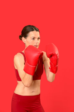 fit sporty woman wearing boxing gloves, sparring, red background