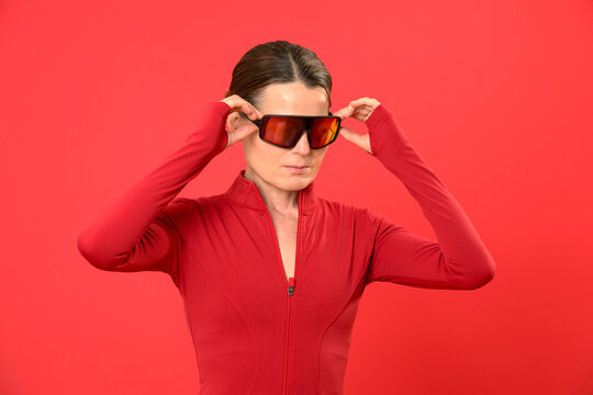 Sporty woman adjusting mirrored sunglasses, red sportswear