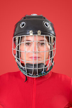female hockey player in a cage helmet and red sportswear, close up portrait