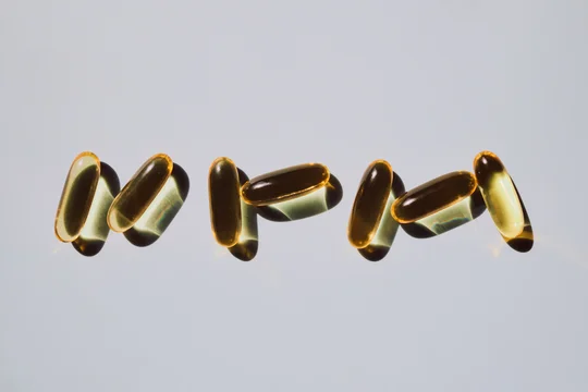 Yellow softgel capsules casting shadows on light background