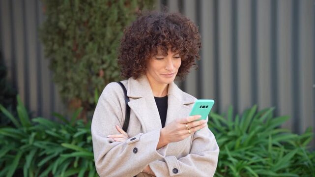 A young woman checks her smartphone in an urban setting with beautiful greenery around