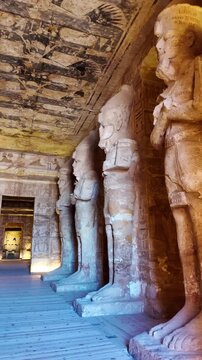 Ancient stone statues of pharaoh ramesses ii lining the grand hall of the abu simbel temple in aswan, with hieroglyphs on the walls