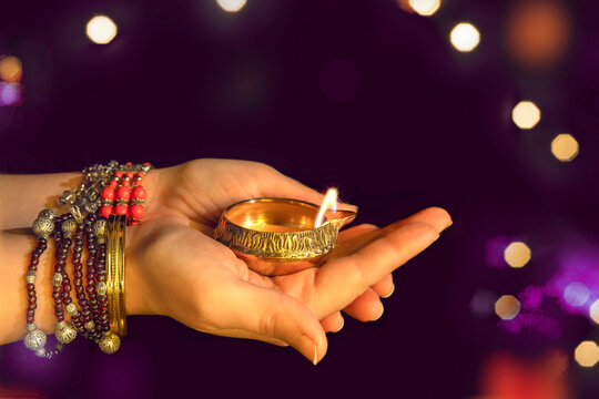 Hands with Diwali lamp diya or Deepavali or Deepawali. Hindu festival of lights. Celebrating in Indian religions Jainism and Sikhism. Offering to the gods, a spiritual rite. Close up, out of focus